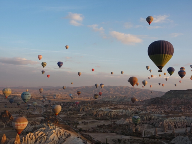 早朝のカッパドキアで奇岩群の上空に多数の熱気球が浮かぶ風景
