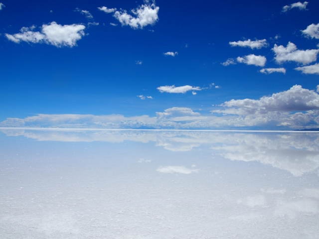澄んだ水面に雲の輪郭がはっきり反射して映るウユニ塩湖