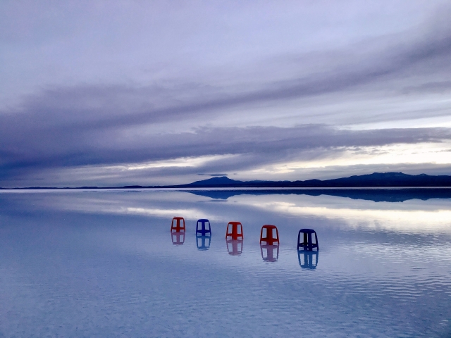 ウユニ塩湖の水面に椅子と空が上下対称に反射して映る風景