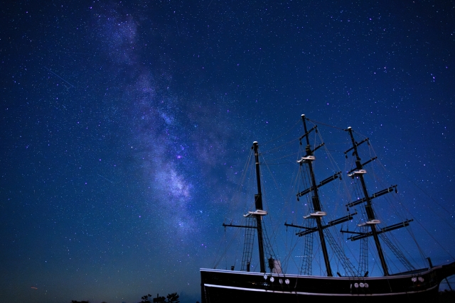 夜の海に浮かぶ帆船のマストと、その上に広がる星空。人の姿は見えず、静かな航海の時間が流れている。