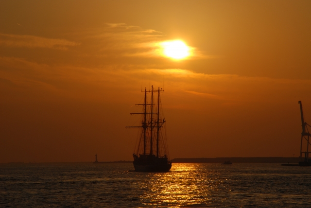 夕暮れの海を進む帆船のシルエットと水平線
