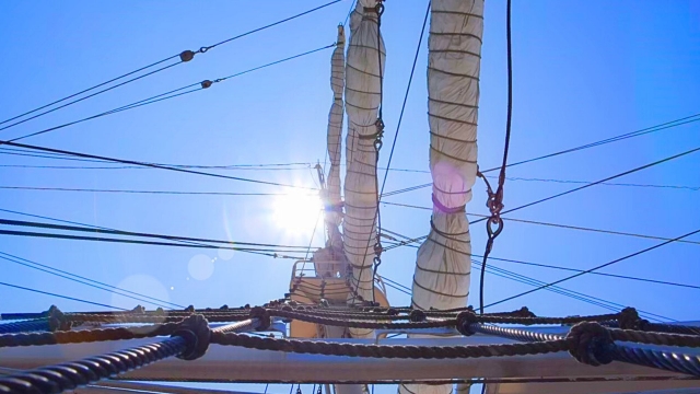 甲板の上から見上げた帆とロープ。張り詰めた索具が風を受け、航海が始まっていることを感じさせる光景