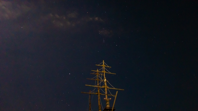 夜空の星を見上げる帆船のマスト。空を基準に方位を知ろうとした航海の様子。