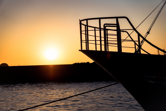 夕暮れの海に浮かぶ現代船のシルエット
