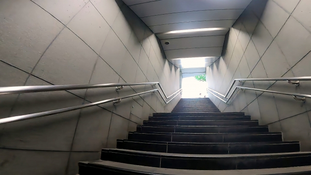 地下通路の階段を上った先に明るい出口が見える風景。建物内の迷いから抜けるような通路