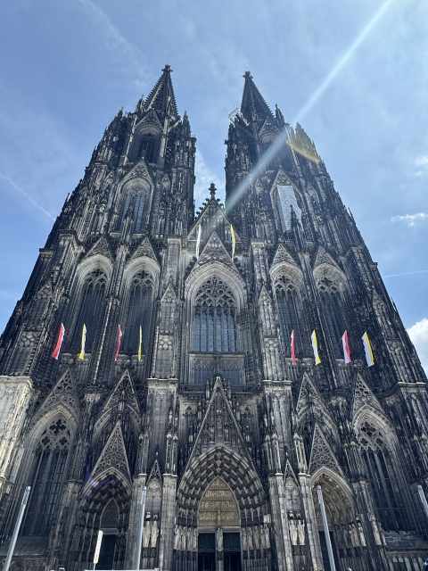 空へ伸びるケルン大聖堂の巨大なゴシック建築を下から見上げた写真