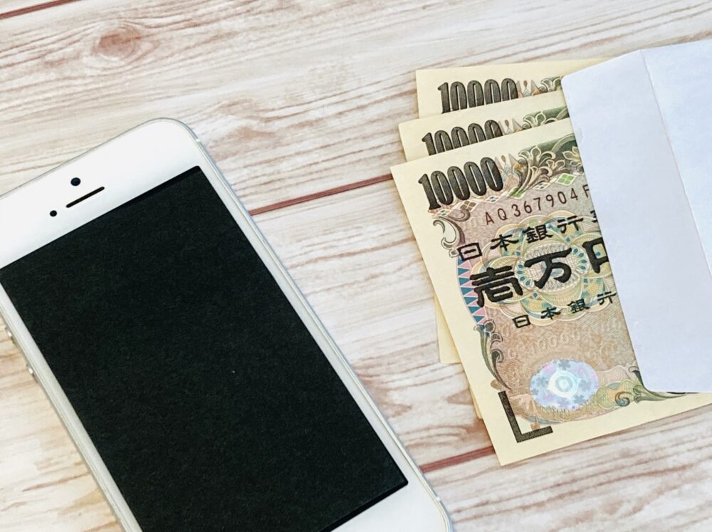 紙幣とスマートフォンが並ぶ、お金の形の変化を表すイメージ